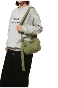 Detail of army green canvas messenger bag featuring adjustable strap and side pocket