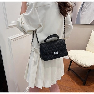 Detailed view of the black quilted crossbody bag with silver twist lock and chain strap