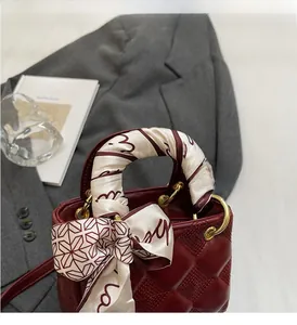 Macro shot of burgundy quilted leather mini handbag with silk scarf wrapped handle