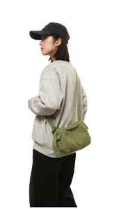 Détail du sac bandoulière en toile vert armée avec bandoulière réglable sur un mannequin