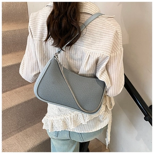 Detail of grey-blue woven underarm bag with silver chain and smooth leather trim