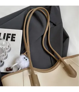 Detail of color-block tote bag with slim shoulder straps and cute furry monster charm
