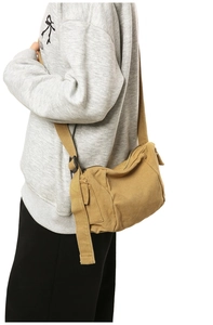 Side view of khaki canvas messenger bag on model showing adjustable strap and texture