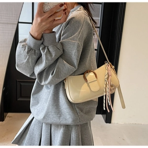 Detail of cream shoulder bag with wooden buckle and colorful braided strap charm