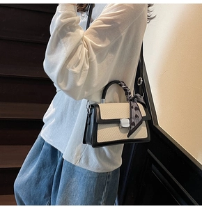 Detail of crossbody bag with silver twist lock and decorative heart print scarf on handle