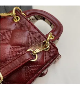 Close-up of red quilted leather handbag featuring polished gold-tone hardware rings