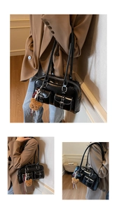 Macro view of black glossy shoulder bag featuring dual buckle pockets and bear charm