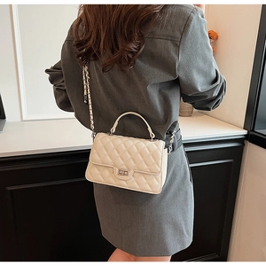 Quilted crossbody bag in creamy white shown on model's shoulder with elegant chain strap