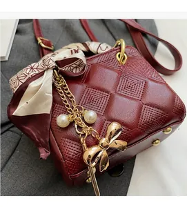 Detailed close-up of burgundy quilted handbag with silk scarf and gold charms