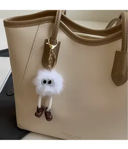 Close-up of creative plush monster charm with big eyes on an ivory tote bag