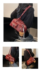 Detail view of burgundy faux leather shoulder bag with utility pockets and bear charm