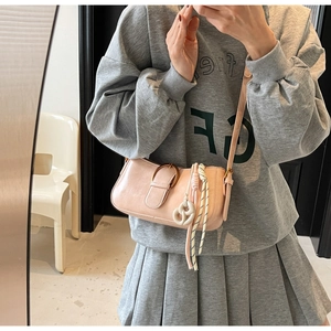 Pink glossy leather shoulder bag featuring a vintage bronze buckle and woven charm