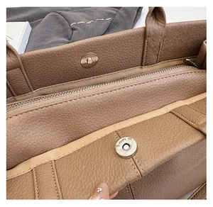 Détail des fermoirs magnétiques argentés et poche zippée dans le sac cabas en cuir