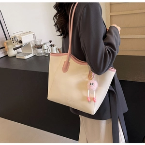 Detailed view of the large capacity beige leather tote bag with a pink plush charm