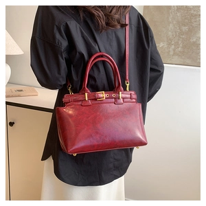Détail du sac docteur vintage rouge foncé en cuir brillant avec boucles métalliques d'or
