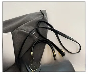 Detail of black crossbody bag featuring gold heart pendant and adjustable leather strap