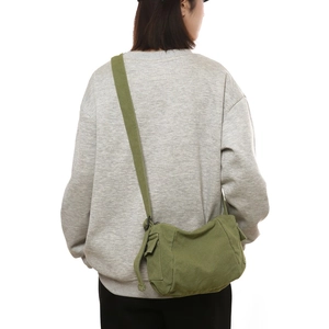 Sacoche minimaliste en toile vert armée portée par une personne pour l'école et le quotidien