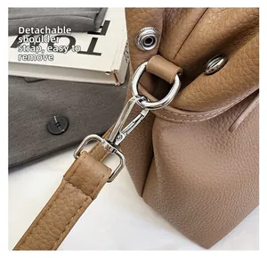 Détail de la serviette en cuir grainé avec fermoir mousqueton argenté et anneau en D