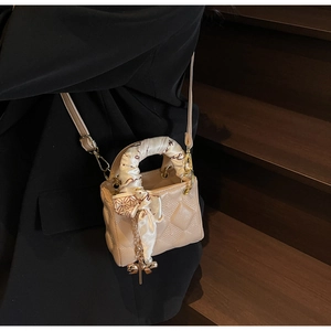 Detail of apricot quilted mini handbag featuring a floral silk scarf and pearl charm