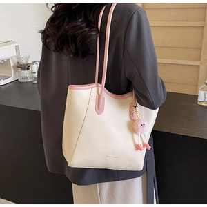Fashionable creamy white tote bag with pink trim and cute plush eye charm on shoulder strap