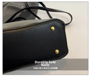 Close-up of black pebble leather handbag base with gold wear-resistant metal feet studs