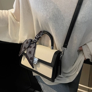 Chic beige woven crossbody bag with black trim and heart-print silk scarf handle detail