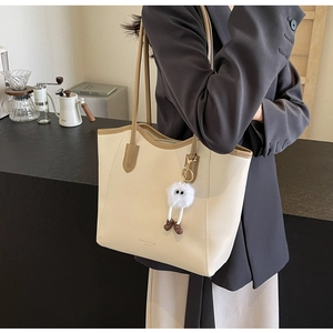Detail of beige faux leather tote bag with monster charm and fashion lettering
