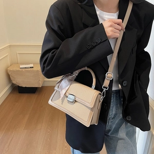 Beige woven crossbody bag with silver buckle and silk scarf handle on model