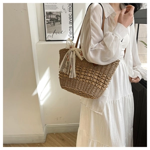 Detailed close-up of straw woven tote bag featuring floral lace ribbon and brown strap