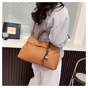 Détail du sac cabas en cuir camel avec pompon décoratif et bandoulière amovible