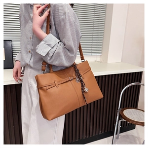 Gros plan d'un sac cabas marron en cuir grainé avec un pendentif floral élégant