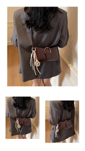 Detail of dark brown glossy leather baguette bag featuring a gold horseshoe buckle