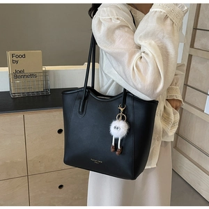 Detail of black tote bag with white plush charm and Fashion trend printed text