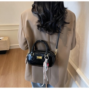 Rückansicht einer schwarzen Mini-Boston-Tasche mit goldener Hardware und Web-Anhänger