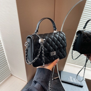 Black quilted rhombic chain bag with silver buckle shown in hand and mirror reflection