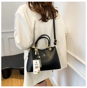 Close-up of a black leather handbag with gold accents on a white blazer outfit