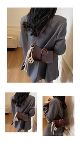Detail of burgundy leather shoulder bag with metallic buckle and woven knot charm accessory