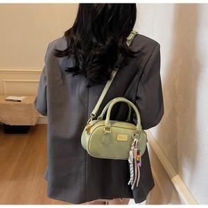 Detailansicht der salbeigrünen Boston-Handtasche mit goldenen Beschlägen und Anhänger