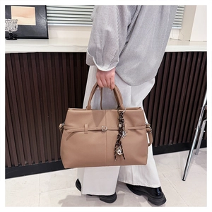 Détail du cuir grainé litchi et du charm en foulard de soie sur le sac fourre-tout