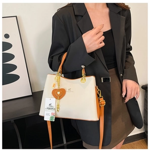 Detail view of cream handbag with brown trim and kangaroo logo on a model