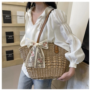 Detailed shot of woven tote bag with lace floral embroidery and brown leather strap