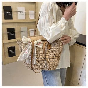 Detail of woven beach tote bag with white lace floral bow and brown leather straps