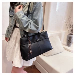 Gros plan du sac cabas en cuir noir avec boucle argentée et pendentif tressé détaillé