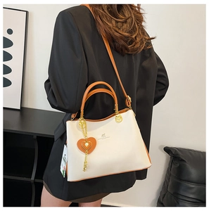 Detail of contrast stitch handbag with gold kangaroo logo and heart pendant charm