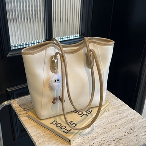 Fashionable beige PU leather tote bag with khaki trim and cute plush monster pendant