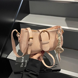 Pink faux leather underarm bag with metal buckle and heart pendant in hand