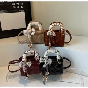 Close-up of quilted leather handbags with decorative silk scarves and pearl bow charms
