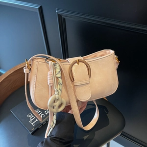 Pink faux leather underarm bag with metal buckle and woven charm on a black chair