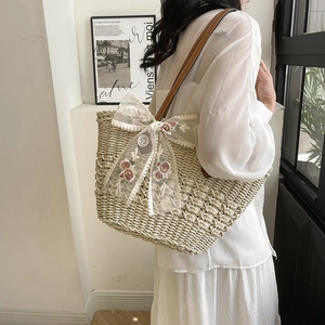 Straw basket tote with brown leather handles and pink floral lace bow for summer beach