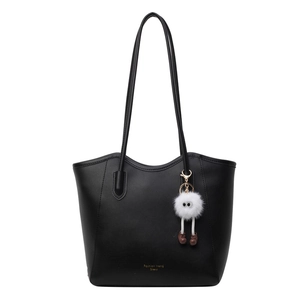 Minimalist black faux leather tote bag with plush white doll charm and gold lettering